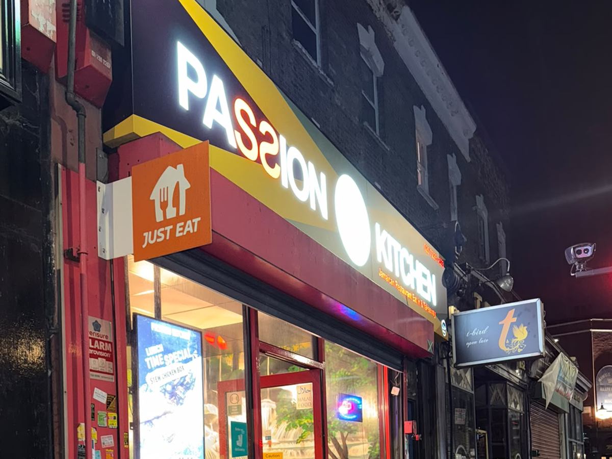 The Passion Kitchen shopfront on Blackstock Road at night, the lit sign reading Passion Kitchen Jamaican Restaurant Eat In and Takeaway.